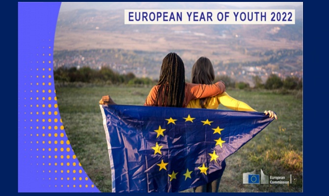 immagine di due ragazze di spalle che guardano un panorama con sulle spalle la bandiera dell'UE