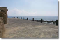 altra vista del pontile del castello con muretto basso sulla sinistra e circondato dal mare