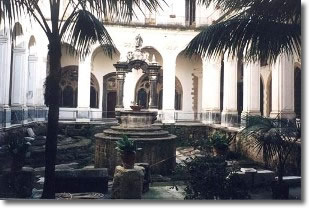 inside of a cloister with colonnade, trees and a well in the centre