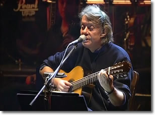 immagine di un uomo che, seduto, canta e suona la chitarra