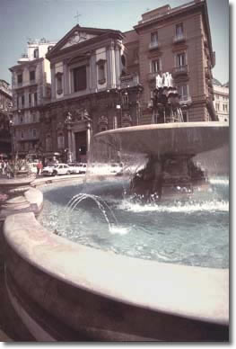 una fontana in primo piano con edifici sullo sfondo