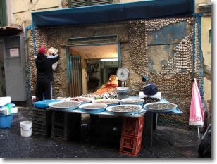 a fishmonger shows the goods in a lane of Naples