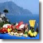 prodotti tipici campani su una tavola imbandita, con sullo sfondo la costiera amalfitana