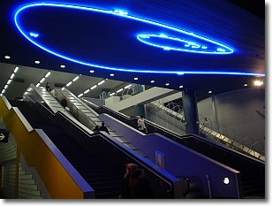 scale mobili di una metropolitana con una installazione artistica di luci