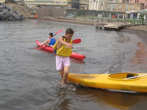 un ragazzo trascina in acqua una canoa di colore giallo