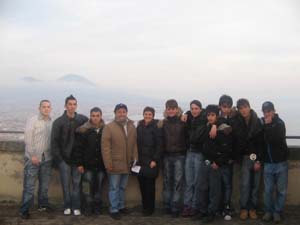 un gruppo di ragazzi in piedi posa per una foto con sullo sfondo il mare e il Vesuvio