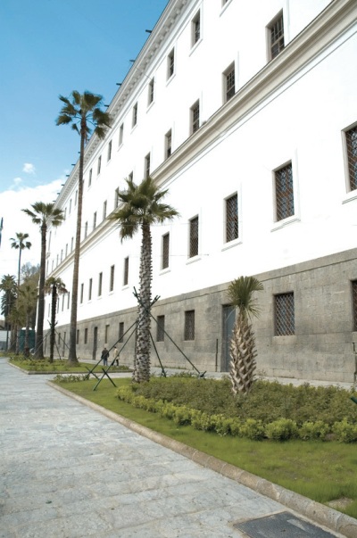 parte frontale di un lungo fabbricato con alberi ed aiuole