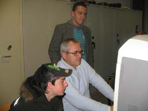 un docente di fronte al computer e due ragazzi accanto a lui
