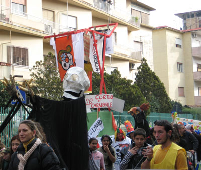 corteo che porta uno stenditoio su cui sono appese le bandiere dei vari movimenti cittadini che si oppongono alle istituzioni