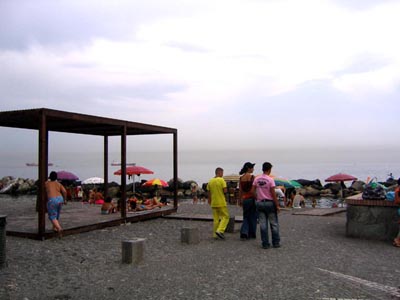 ombrelloni lungo la riva e tre persone che passeggiano sulla spiaggia