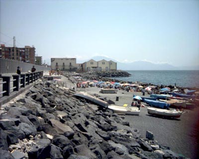 bagnanti sotto gli ombrelloni e barche a remi sulla spiaggia