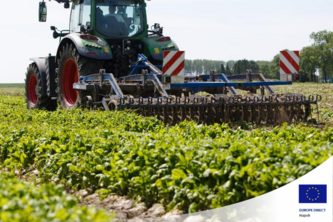 Immagine di una campagna coltivata con un trattore al lavoro